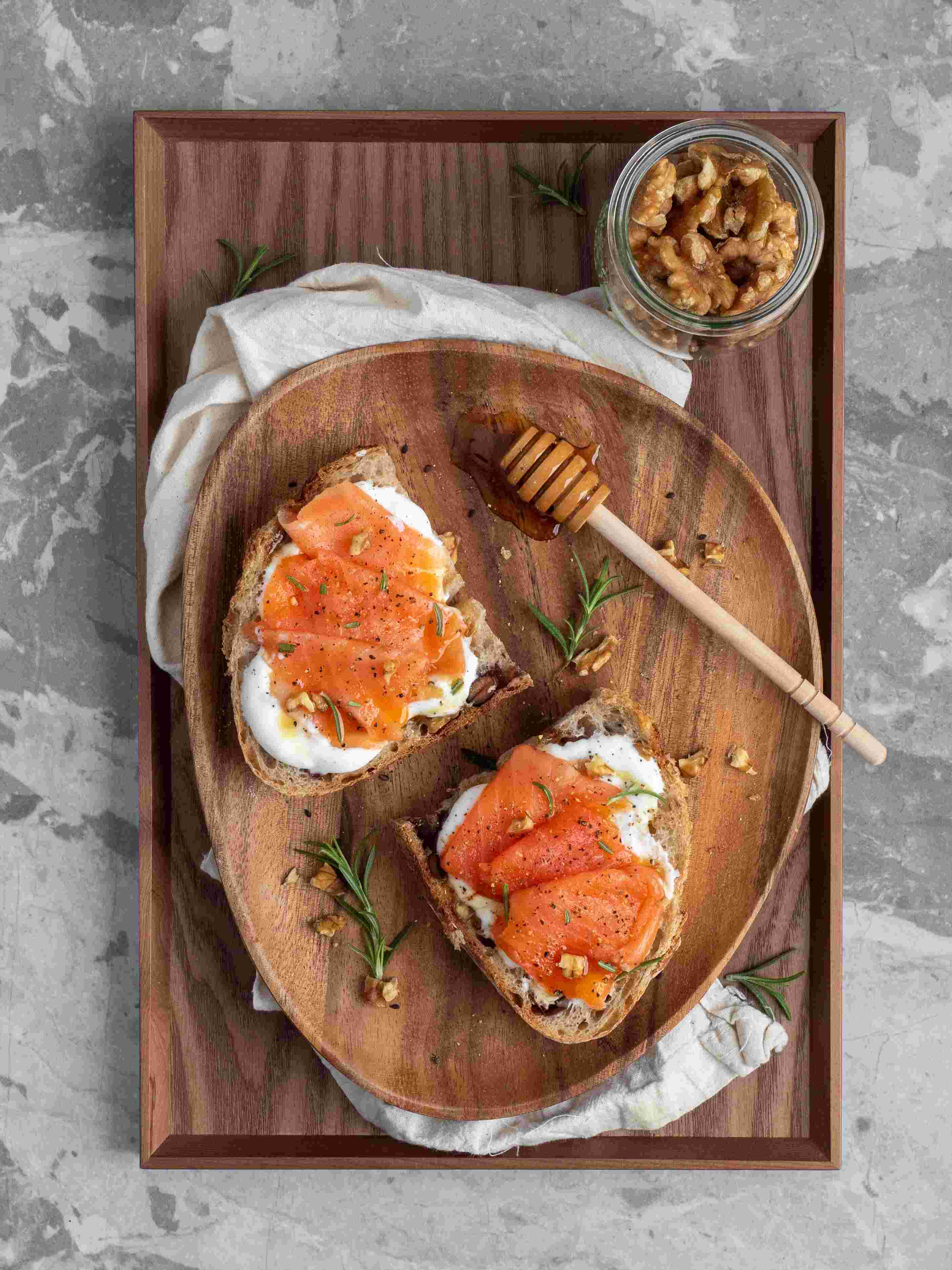 Two slices of bread with salmon and egg on a brown plate